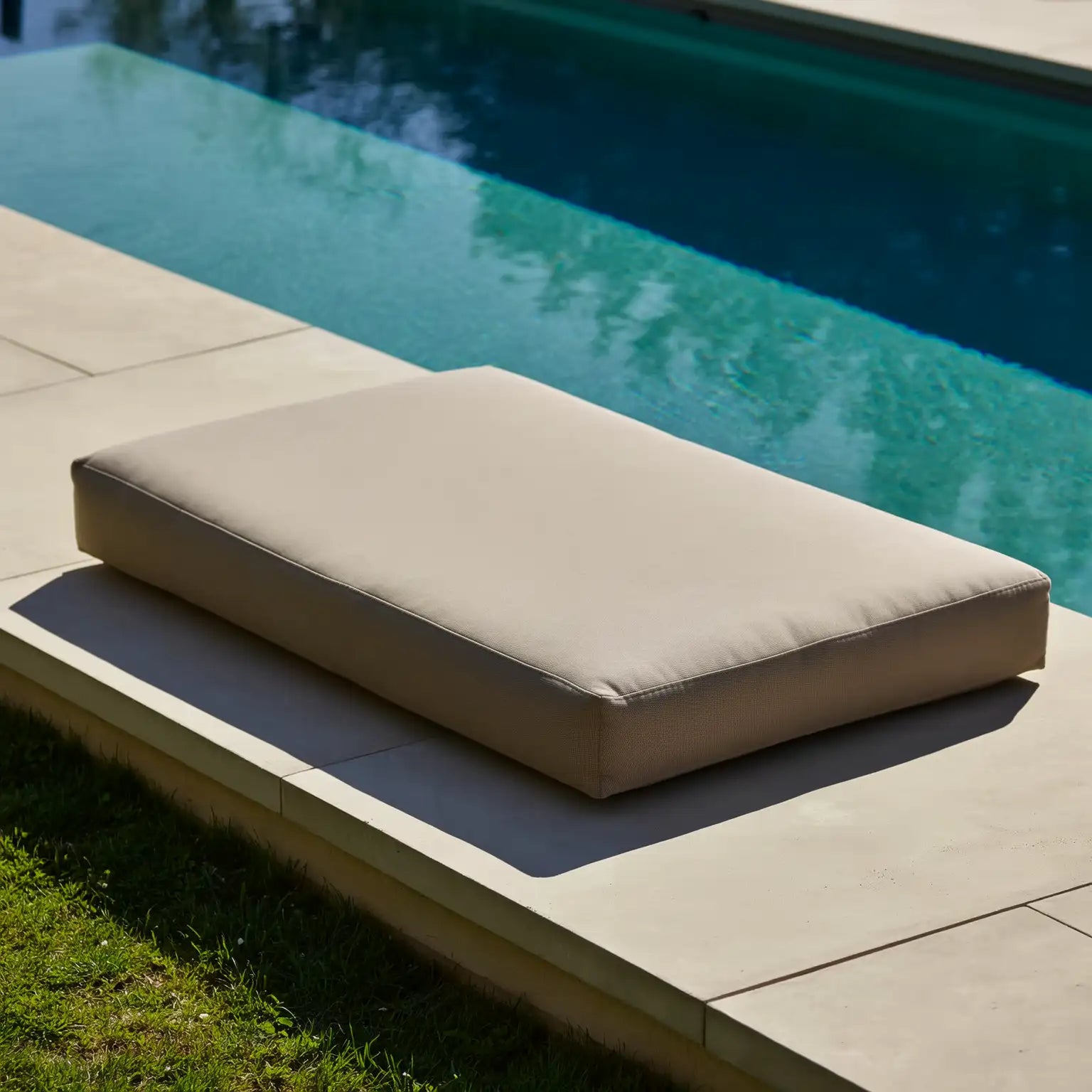 Coussin beige rectangulaire pour piscine avec bords cousus nets et une surface rembourrée moelleuse.
