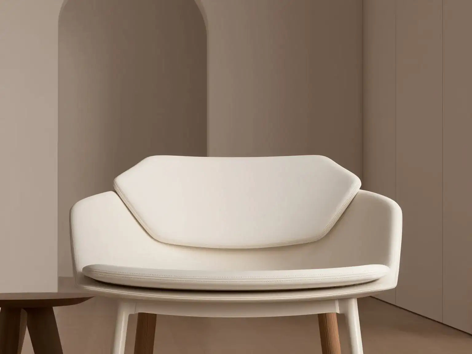 Fauteuil moderne tapissé de blanc avec des pieds en bois élégants.
